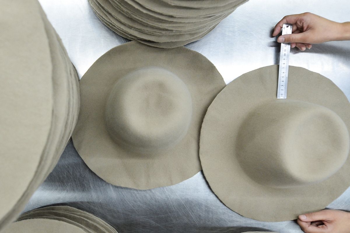 Craftsperson holding and checking a finished hat